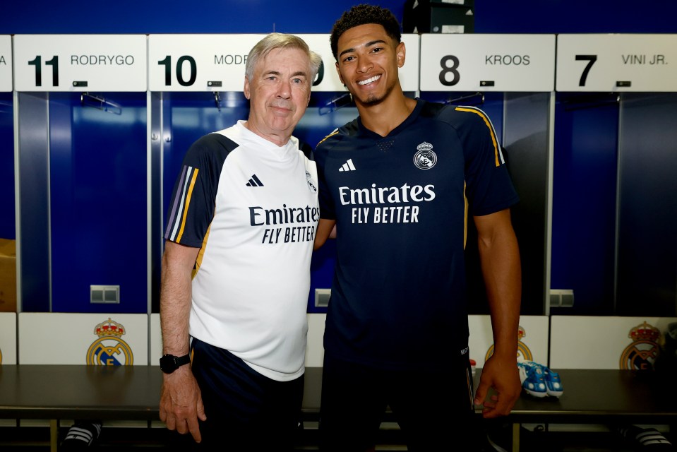 two men posing for a picture in a locker room wearing emirates fly better shirts