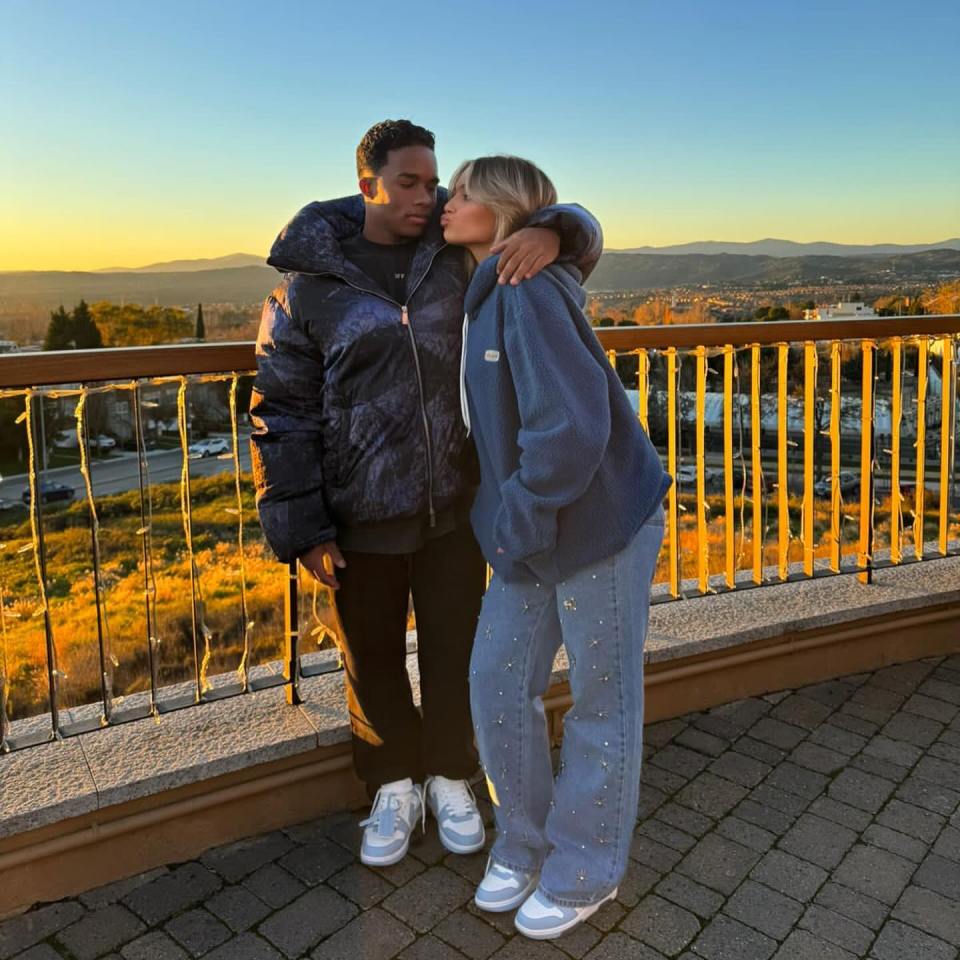 a woman kisses a man on the cheek in front of a railing