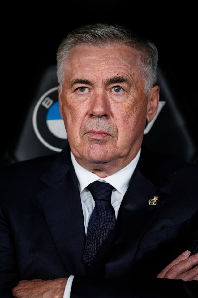 a man in a suit and tie stands with his arms crossed in front of a bmw logo