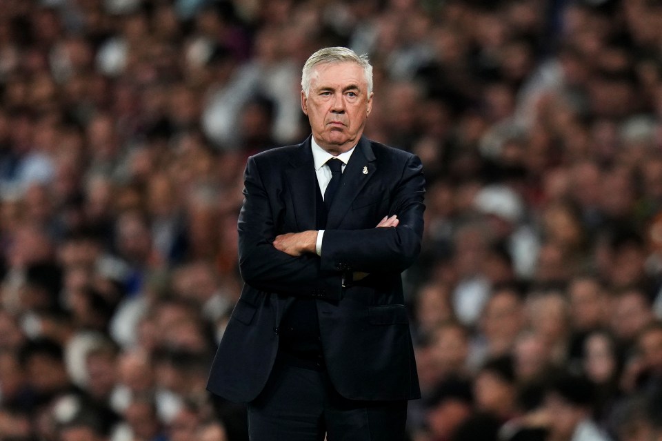 a man in a suit stands with his arms crossed in front of a crowd