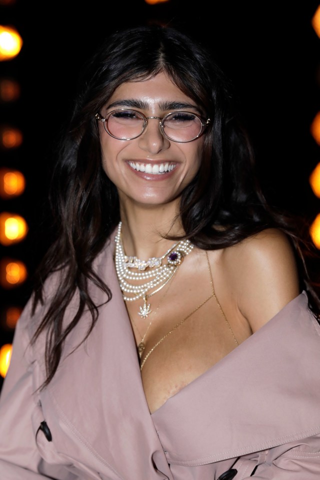 a woman wearing glasses and a pearl necklace smiles for the camera