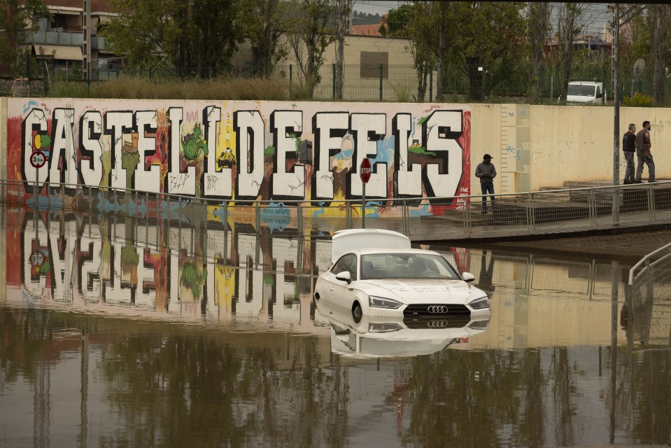 a car is floating in the water in front of a wall that says castell defels