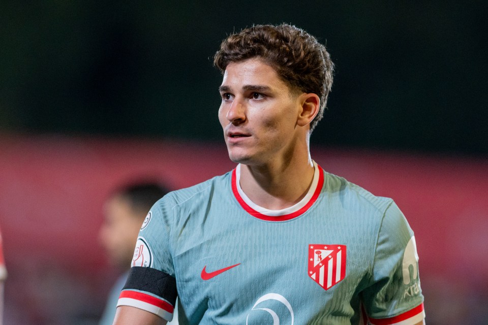 a soccer player wears a grey jersey with red and white stripes