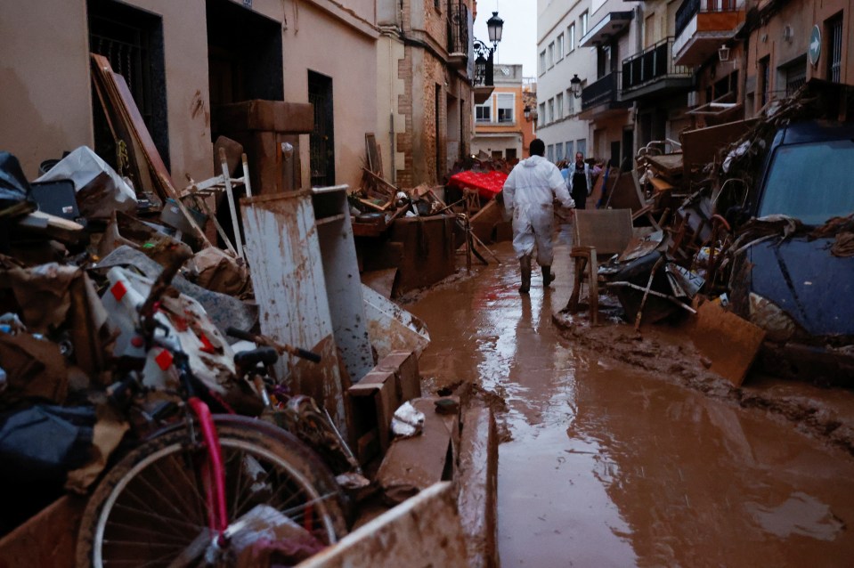 a man in a white suit walks through a flooded street