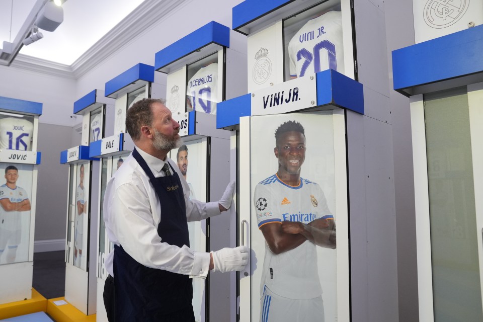 a man wearing white gloves is standing in front of a display of jerseys with the number 20 on them