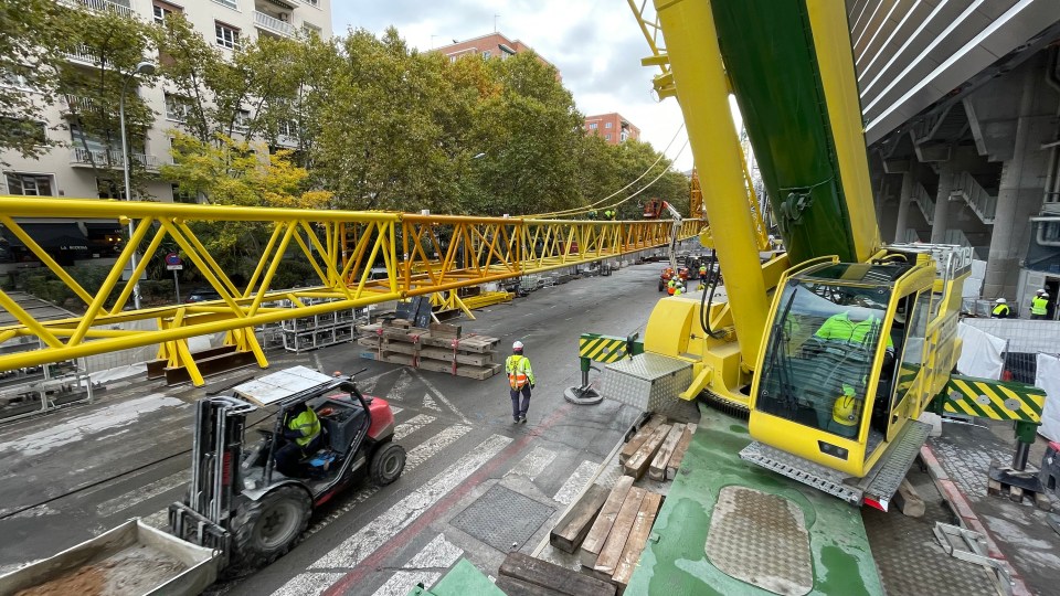 Large crane lifting a retractable roof section at a stadium.