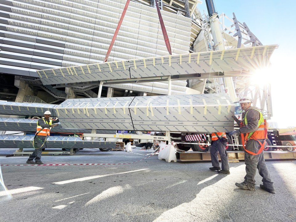 Workers installing metal facade slats on the Santiago Bernabéu Stadium.