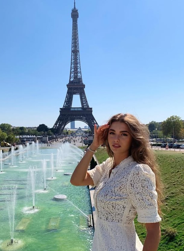 Woman in white dress in front of Eiffel Tower.