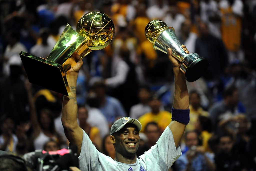 Kobe Bryant #24 of the Los Angeles Lakers holds up the Larry O'Brien trophy and the Bill Russell MVP trophy after the Lakers defeated the Orlando M...