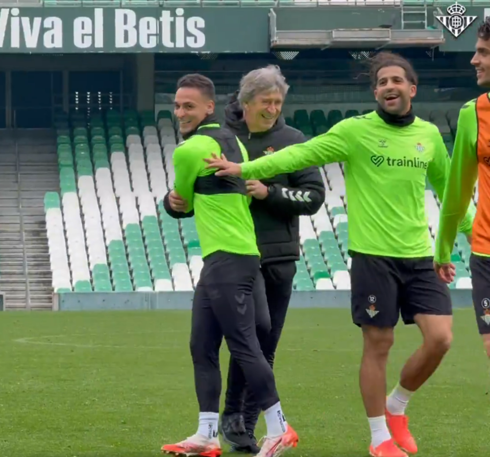 Soccer players and coach laughing together at a stadium.