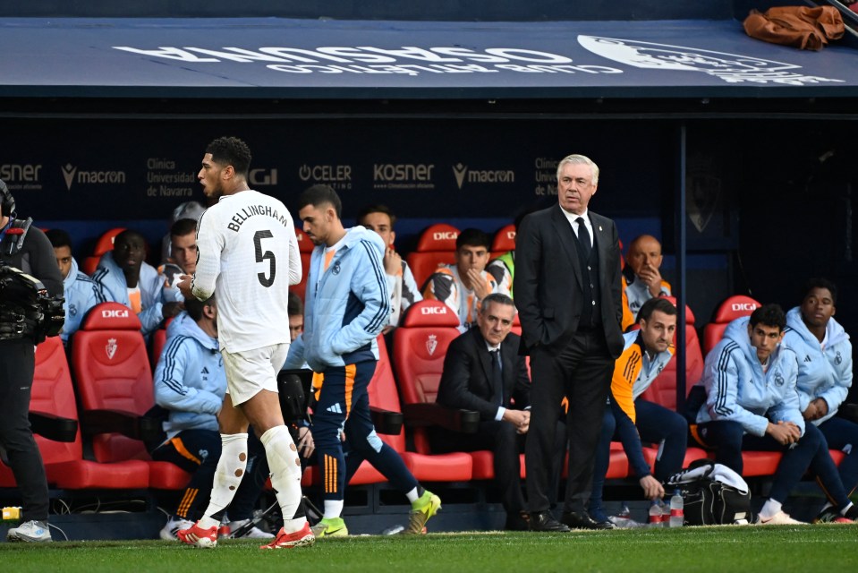 Jude Bellingham leaving the pitch after receiving a red card, with Carlo Ancelotti looking on.