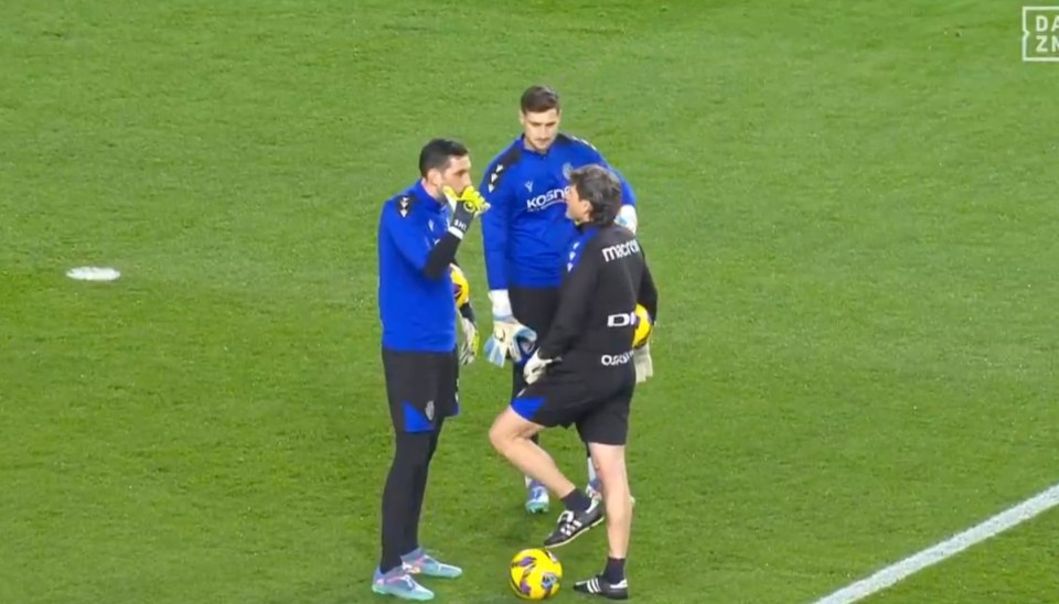 Three soccer goalkeepers talking on the field.