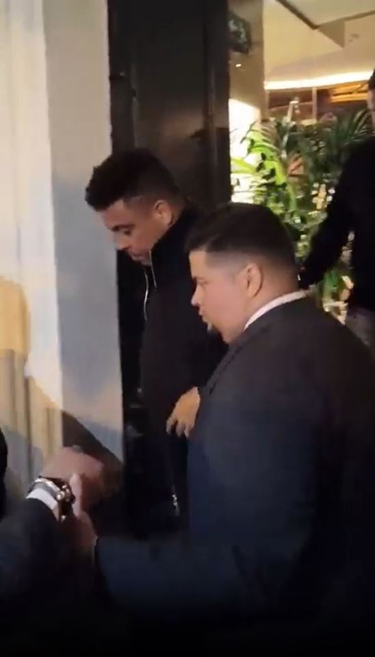 Ronaldo leaving a restaurant, assisted by someone.